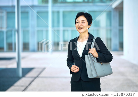 Middle business woman in a suit standing with a smartphone 115870337