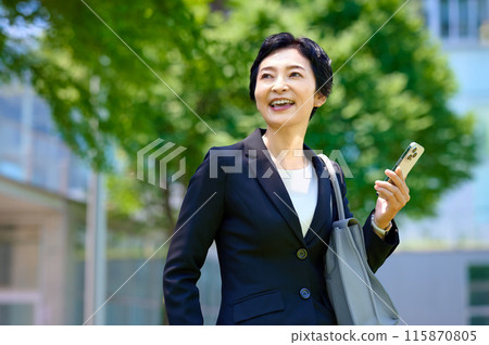 Middle business woman in a suit standing with a smartphone 115870805