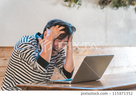 亞洲男子在咖啡館/餐廳看電腦時抱著頭（故障/損壞/麻煩/震驚） 115871352
