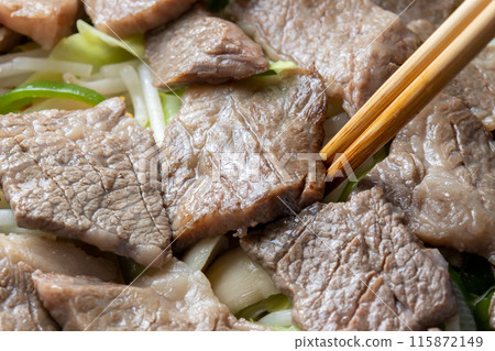 A close-up of a cooking scene of beef and vegetables being stir-fried in a frying pan. 115872149