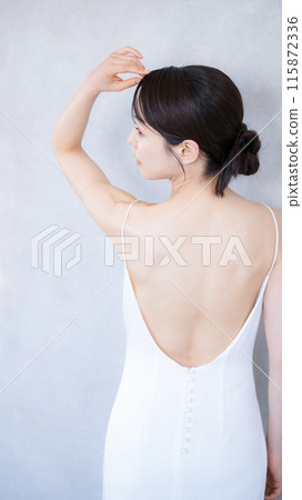 Profile of a woman wearing a beautiful white dress with an open back. Close-up of the back. Image for beauty treatments, hair removal, and slimming. Profile of a woman wearing a beautiful white dress with an open back. Close-up of the back. Image for beauty treatments, hair removal, and slimming. 115872336
