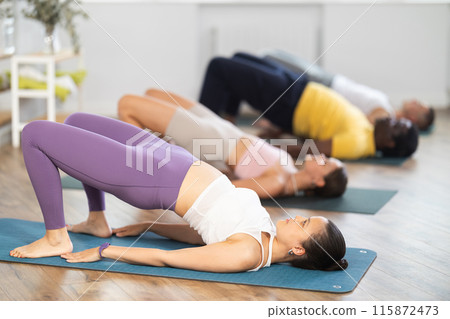 Asian woman performing Setu Bandha Sarvangasana in yoga class Asian woman performing Setu Bandha Sarvangasana in yoga class 115872473
