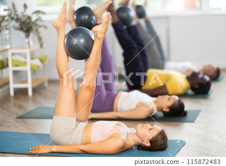 Young woman doing pilates with soft ball in group Young woman doing pilates with soft ball in group 115872483