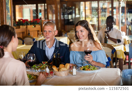 Friends dining and drinking wine at restaurant 115872501