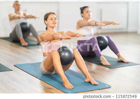 Young woman doing pilates with soft ball in group Young woman doing pilates with soft ball in group 115872549