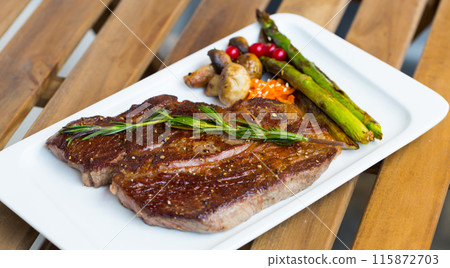 Roasted veal steak on wooden background 115872703