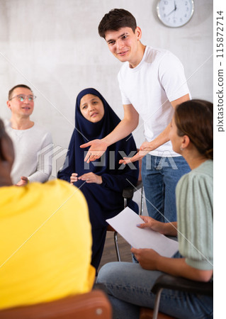 Emotional young guy talking to colleagues in office lounge room 115872714