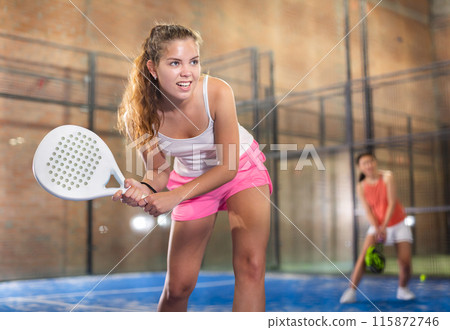 Young beautiful woman with racket playing padel 115872746