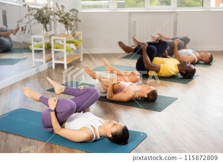 Group of men and women doing yoga in studio Group of men and women doing yoga in studio 115872809