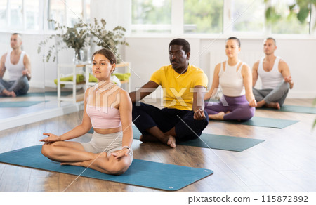 Group of men and women doing yoga in studio Group of men and women doing yoga in studio 115872892