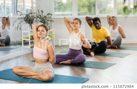 Group of men and women doing yoga in studio Group of men and women doing yoga in studio 115872984