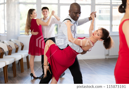 Black man enjoying impassioned merengue with woman in red in studio Black man enjoying impassioned merengue with woman in red in studio 115873191