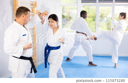 Middle-aged woman attendee of karate classes fighting with her opponent in sports hall 115873280