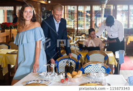 Handsome gentleman helping young attractive woman with her chair Handsome gentleman helping young attractive woman with her chair 115873343
