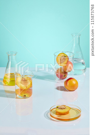 The photo of high angle view at the white table top in laboratory, for advertising products made from peach. A petri dish with yellow fluid placed in front of plenty lab instrument and fresh peaches 115873768