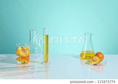 The front view photo to advertise product has natural fruit ingredient like peach, over the blue color texture. Yellow extract from peach and peaches, contained in lab glassware placed on white table The front view photo to advertise product has natural fruit ingredient like peach, over the blue color texture. Yellow extract from peach and peaches, contained in lab glassware placed on white table 115873774
