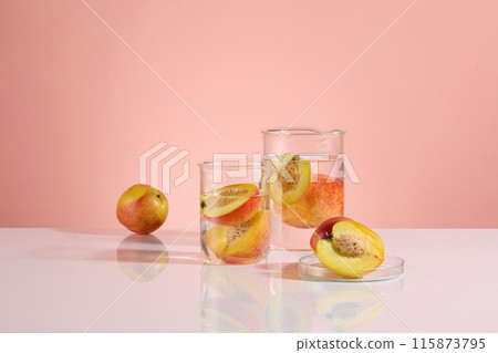 The photo with pink background was taken from front angle, some glass beaker containing fresh peach soaking in transparent fluid, next to a petri dish. Blank space for designing and advertising 115873795
