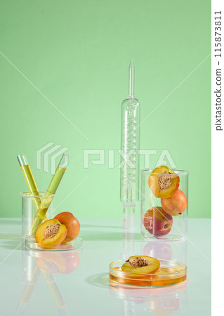 Product of peach promotional photo with laboratory layout on green background. On top of the white table displaying some types of experiment glass utensils, which having fresh peaches placed Product of peach promotional photo with laboratory layout on green background. On top of the white table displaying some types of experiment glass utensils, which having fresh peaches placed 115873811