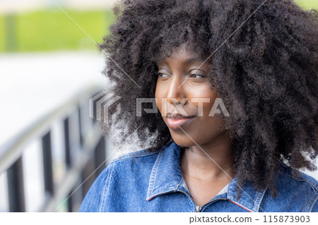A stylish young woman showcasing her natural hair style in an outdoor setting under natural sunlight A stylish young woman showcasing her natural hair style in an outdoor setting under natural sunlight 115873903
