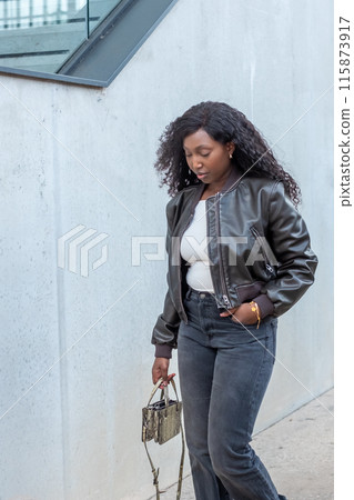 Stylish woman exudes confidence in a leather jacket, walking outdoors with a fashionable attitude Stylish woman exudes confidence in a leather jacket, walking outdoors with a fashionable attitude 115873917