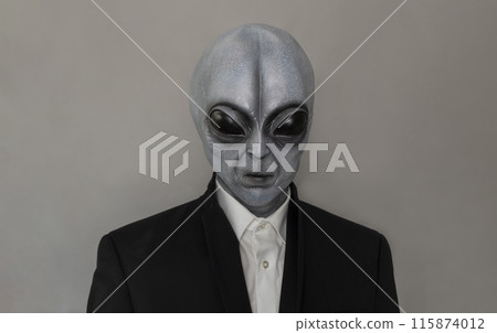 Portrait Of Alien Wearing Suit Gray Background. World UFO Day. Extra Terrestrial Being, Unidentified Flying Objects. Vertical Plane. Grey Humanoid. 115874012