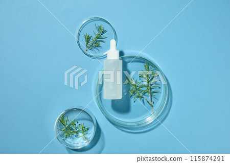 Natural medicine and cosmetic research with a dropper bottle decorated with three petri dishes of tea tree leaves. Container packaging of skin care branding with Tea tree extract Natural medicine and cosmetic research with a dropper bottle decorated with three petri dishes of tea tree leaves. Container packaging of skin care branding with Tea tree extract 115874291