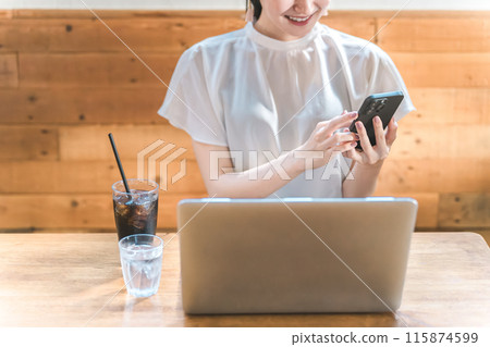 Asian businesswoman teleworking and working using a computer and smartphone in a cafe or coffee shop 115874599