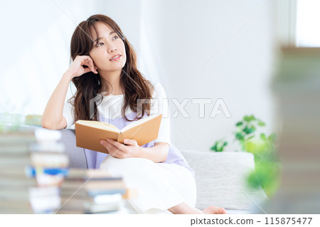 Young woman reading a book in the living room 115875477
