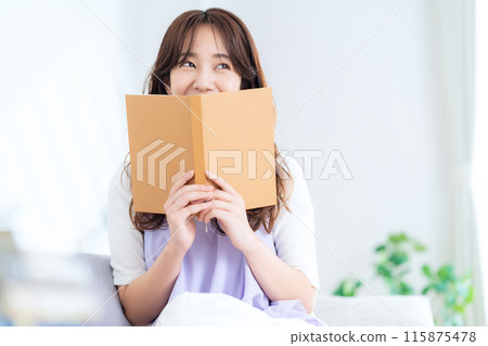 Young woman reading a book in the living room 115875478