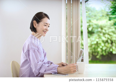 中年婦女在客廳喝咖啡時看著電腦 115875558