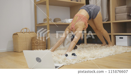 Young Sport Women look at laptop online trainer home fitness workout exercise in living room. Woman using laptop on floor in sportswear arms stretching body weight traning. Healthy lifestyle concept Young Sport Women look at laptop online trainer home fitness workout exercise in living room. Woman using laptop on floor in sportswear arms stretching body weight traning. Healthy lifestyle concept 115876607
