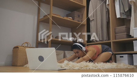 Young Sport Women look at laptop online trainer home fitness workout exercise in living room. Woman using laptop on floor in sportswear arms stretching body weight traning. Healthy lifestyle concept Young Sport Women look at laptop online trainer home fitness workout exercise in living room. Woman using laptop on floor in sportswear arms stretching body weight traning. Healthy lifestyle concept 115876610