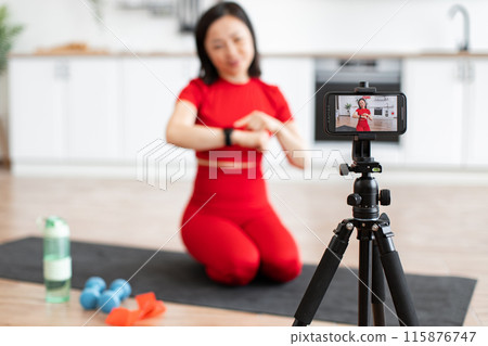 Sporty woman in red talks about smart watch during a fitness video Sporty woman in red talks about smart watch during a fitness video 115876747