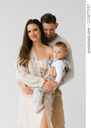 Portrait of a happy young family with a one-year-old son in their arms Portrait of a happy young family with a one-year-old son in their arms 115877317
