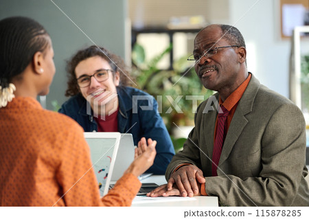 Portrait of smiling senior man discussing ideas in business meeting with young colleagues in office copy space Portrait of smiling senior man discussing ideas in business meeting with young colleagues in office copy space 115878285