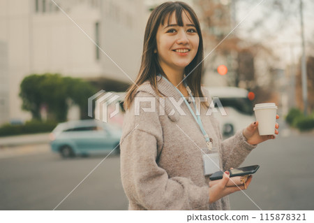 A 20-something office lady looking at the camera while taking out a cup of coffee during her break 115878321