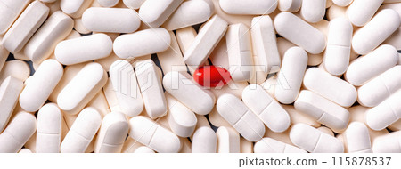 Medicine background from bunch white pills and one red capsule in the middle, macro. 115878537