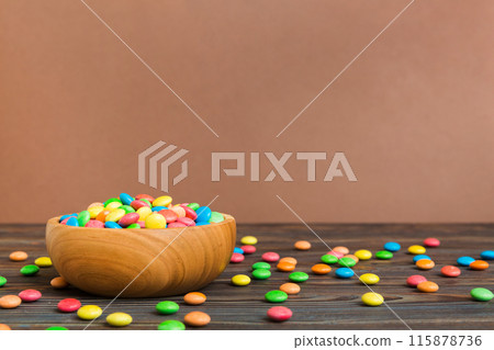 Multicolored candies in a bowl on a colored background. birthday and holiday concept. Top view with copy space 115878736