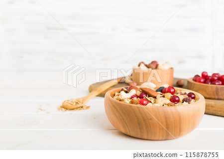 Cooking a wholesome breakfast. Granola with Various dried fruits and nuts in a bowl. The concept of a healthy dessert. Flat lay, top view with copy space Cooking a wholesome breakfast. Granola with Various dried fruits and nuts in a bowl. The concept of a healthy dessert. Flat lay, top view with copy space 115878755