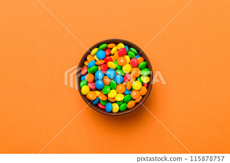 Multicolored candies in a bowl on a colored background. birthday and holiday concept. Top view with copy space 115878757