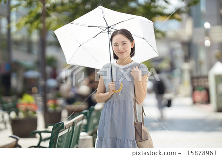 一位年輕女子撐著陽傘穿過城市 一位年輕女子撐著陽傘穿過城市 115878961