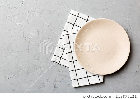 Top view on colored background empty round white plate on tablecloth for food. Empty dish on napkin with space for your design Top view on colored background empty round white plate on tablecloth for food. Empty dish on napkin with space for your design 115879121