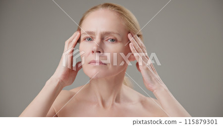 Anti age, Beauty, health and dry skin care concept - beautiful middle-aged mature Caucasian woman in her 50s touching her face skin and looking at the camera with a slight smile 115879301