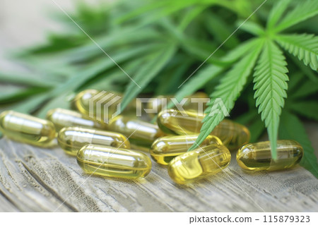 Hemp oil capsules with cannabis leaves on wooden surface promoting natural wellness 115879323