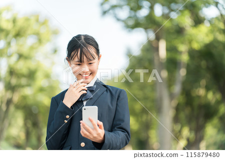 穿著制服和西裝外套的國中女生和高中女生看著自己的智慧型手機時感到驚訝、高興、驚訝。 115879480