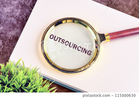 Copy space. Business concept. OUTSOURCING symbol written through a magnifying glass on a blank sheet of notepad Copy space. Business concept. OUTSOURCING symbol written through a magnifying glass on a blank sheet of notepad 115880630
