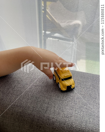 A child's hand is playing with a yellow small toy car A child's hand is playing with a yellow small toy car 115880811