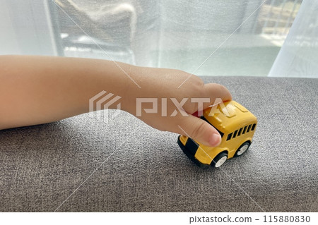 A child's hand is playing with a yellow small toy car A child's hand is playing with a yellow small toy car 115880830