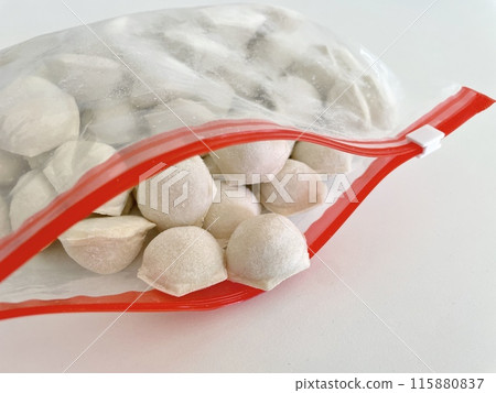 frozen dumplings fly out of an open bag with a red zipper 115880837