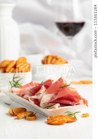 Prosciutto, spicy bruschetta crackers and glass of red wine. Prosciutto, spicy bruschetta crackers and glass of red wine. 115881264